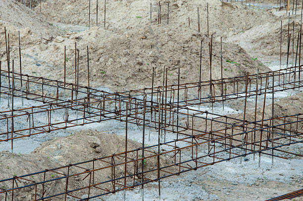 istock Framework for a building is laid out on a construction site. The ground is mostly bare, with mounds of dirt around the area 2221711990