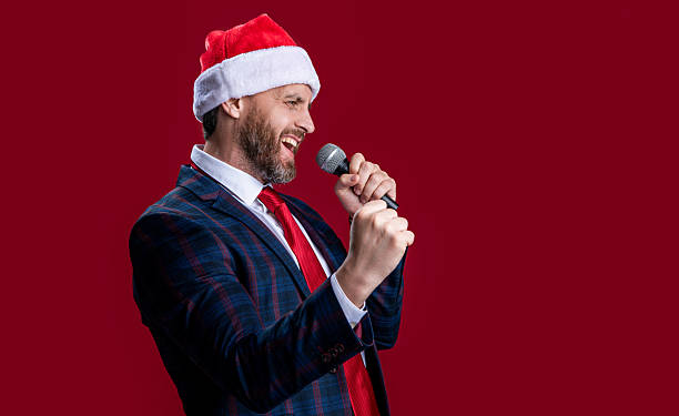 istock christmas event host man singing in santa hat, copy space. event host man singing with microphone 2221712811