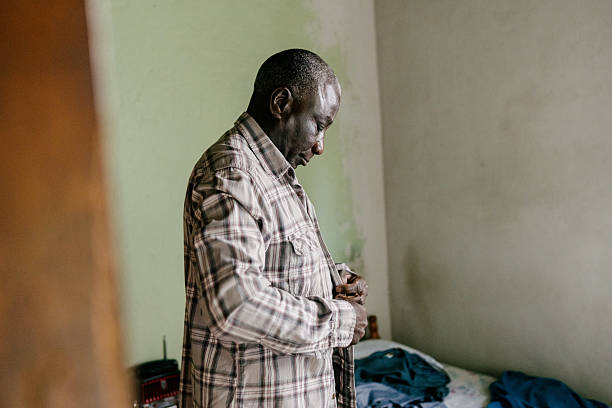 istock Senior man buttoning shirt in humble home 2221715172