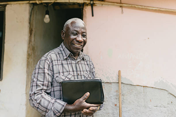 istock Senior holding Bible and smiling near rustic wall 2221715269