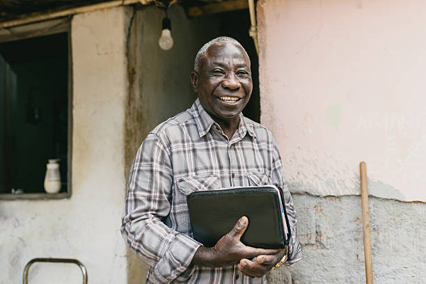 Senior holding Bible and smiling near rustic wall