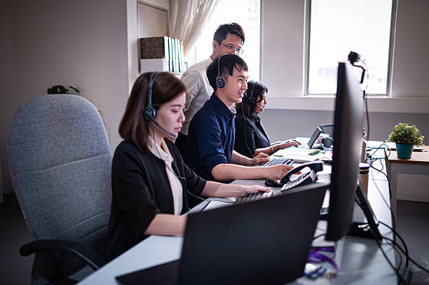 istock Customer support representatives wearing headsets and working late at their work desk in call center 2221720145