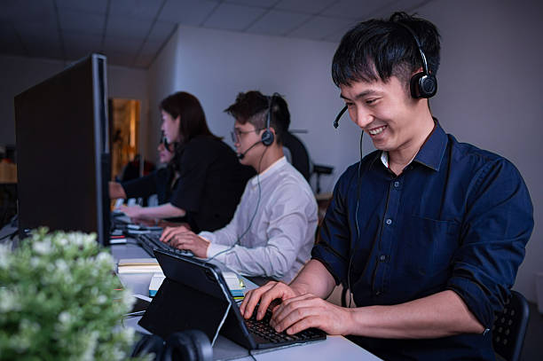 istock Customer support representatives wearing headsets and working late at work desk in call center 2221720171