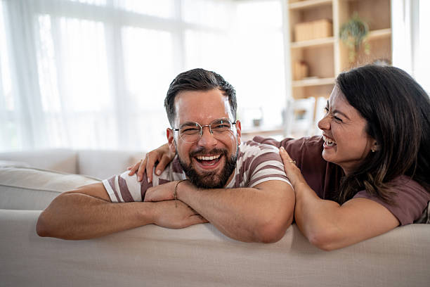istock Happy couple laughing together on sofa at home 2221724576