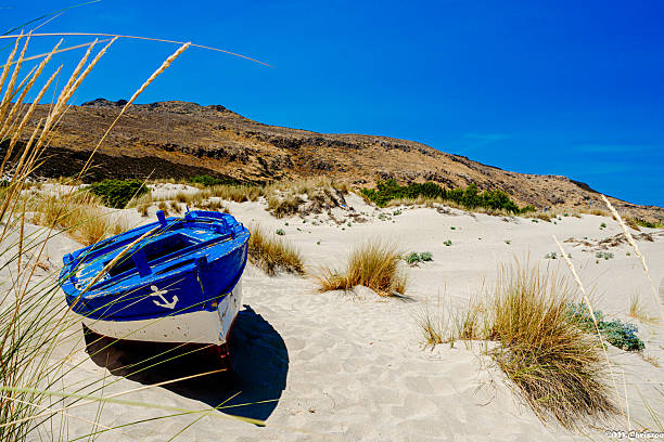 Sandy beach with dunes and sun umbrellas on a clear summer day in Elafonissos, Greece