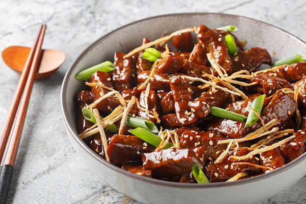 Beef ginger with tender strips of flank steak in a sweet sauce spiked with plenty of ginger and sesame closeup in the bowl. Horizontal stock photo