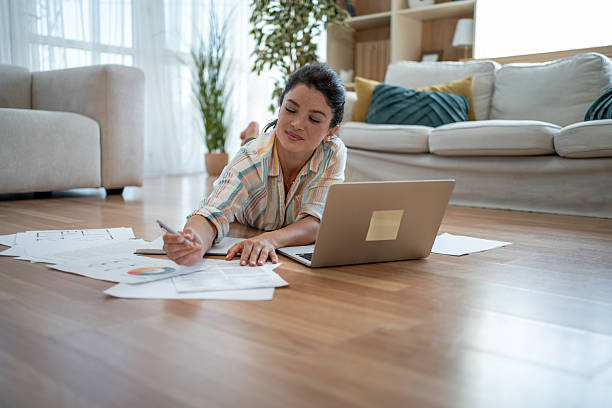 istock Young woman working from home lying on the floor analyzing documents 2221743252