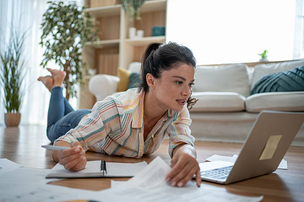 istock Focused young woman lying on floor working from home using laptop 2221743265