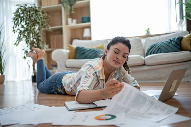 istock Young woman lying on the floor working from home analyzing documents 2221743268