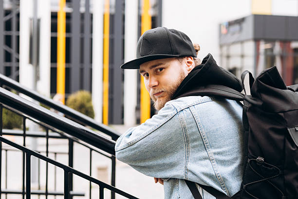 istock Smiling young bearded man in cap leaning on stair railing looking at camera. 2221744710