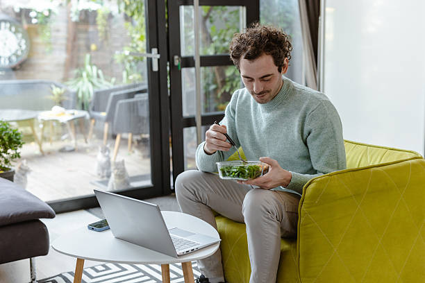istock Man enjoys healthy vegetarian snack while working remotely in modern living room 2221746415