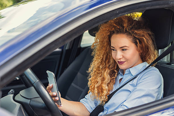 istock Beautiful woman being distracted whilst driving 2221746552