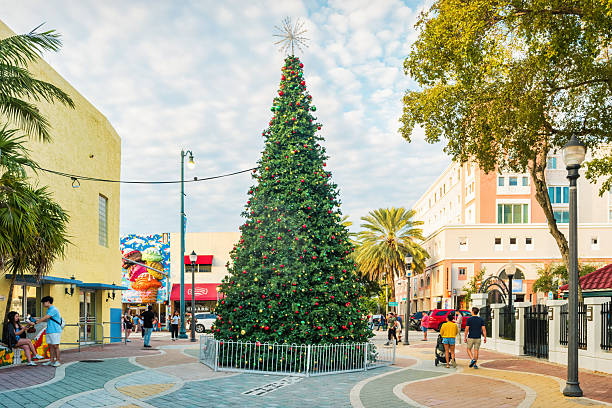 Pedestrians walk past the Christmas tree in Domino Park, Little Havana district, Miami, Florida, USA on cloudy day.