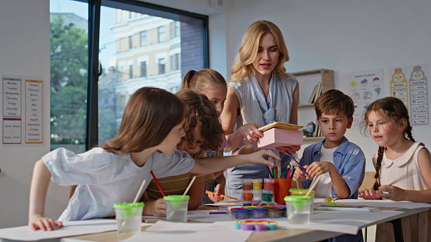 istock Teacher helping students art activity at primary school. Engaged pupils creating 2221755029