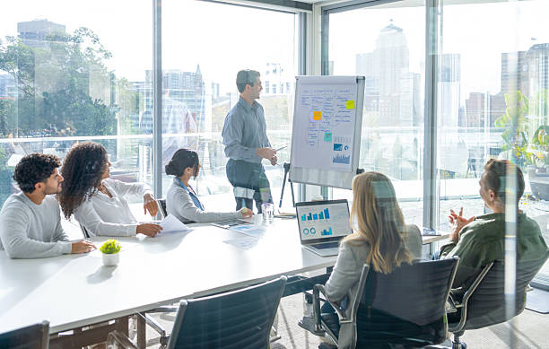 istock Business people watching a presentation on the whiteboard. A man is writing on the whiteboard with charts and graphs. 2221761713
