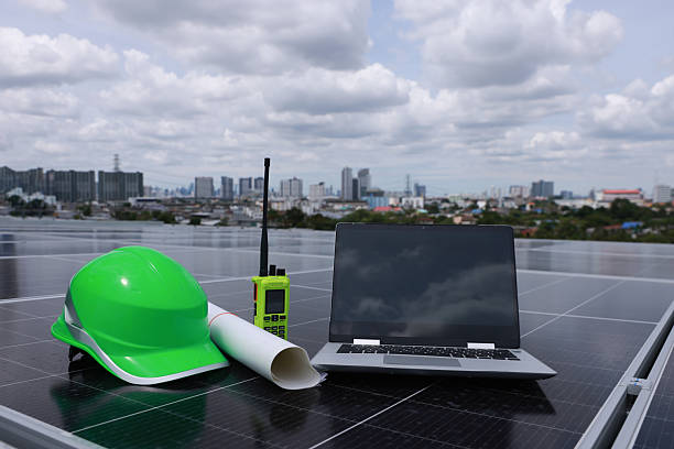istock Green safety hard hat blue print drawing laptop and walkie-talkie placed on a solar panel, symbolizing commitment to green energy, renewable power, and zero-carbon alternative energy solutions 2221765395