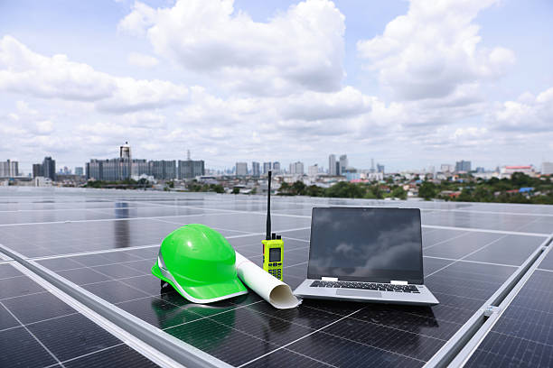 istock Green safety hard hat blue print drawing laptop and walkie-talkie placed on a solar panel, symbolizing commitment to green energy, renewable power, and zero-carbon alternative energy solutions 2221765397