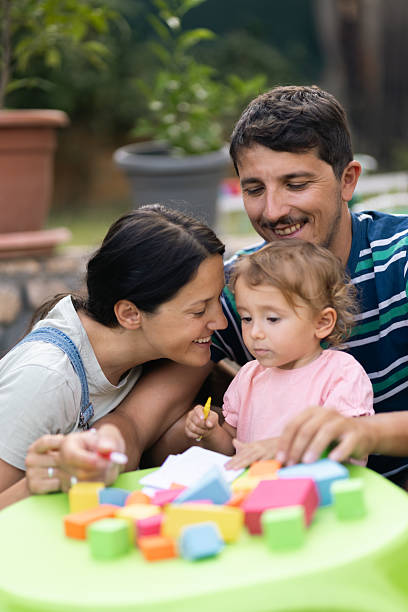 istock Happy parents spending quality time with their young child while playing with colorful blocks outdoors 2221773557