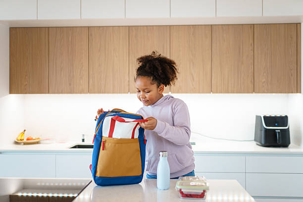 istock Independent Girl Packing Lunch with Backpack in Modern Kitchen 2221775141