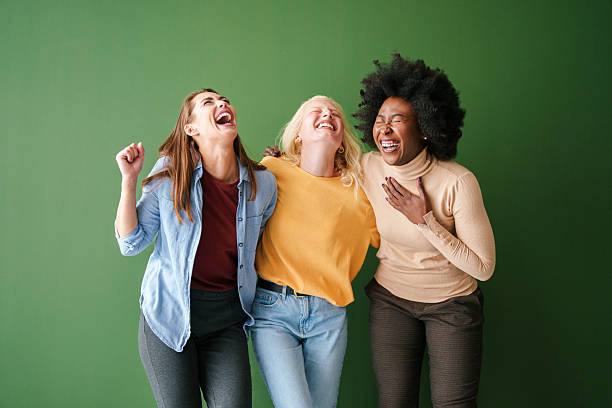 istock Three Multicultural Friends Laughing Joyfully Against a Green Backdrop in Casual Colorful Clothing 2221779891