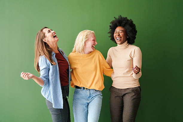 istock Three Diverse Friends Laughing and Bonding Against a Green Backdrop 2221779894