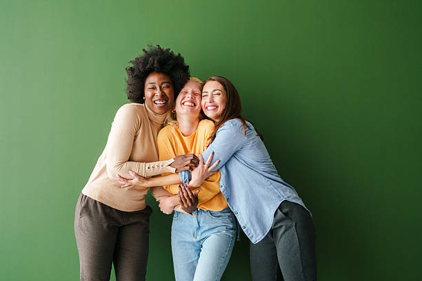 istock Three Multicultural Friends Sharing a Joyful Embrace Against a Vibrant Green Backdrop 2221779897