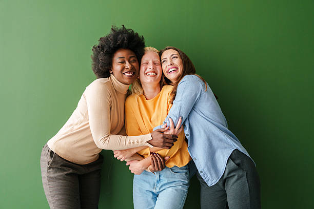 istock Three Multicultural Friends Laughing Together Against a Green Solid Backdrop in Warm, Casual Attire 2221779899