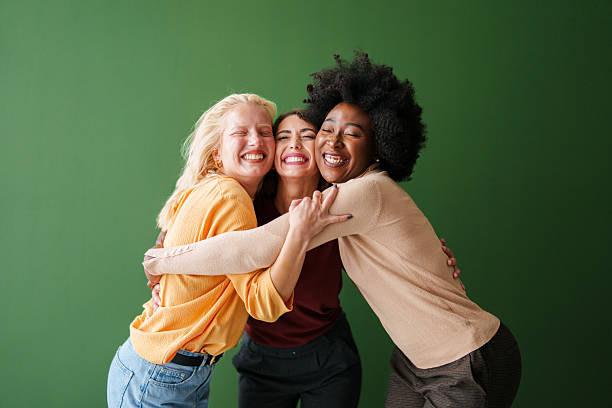 istock Three Multicultural Friends Embracing Joyfully Against a Bright Green Background 2221779903