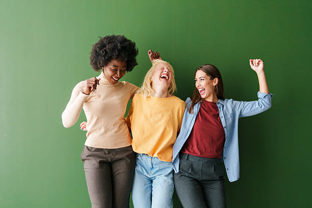 istock Three Multicultural Friends Laughing Joyfully Against a Bold Green Backdrop 2221779904