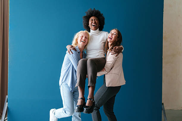 istock Three Multicultural Friends Laughing Together Against a Vibrant Blue Backdrop 2221779962