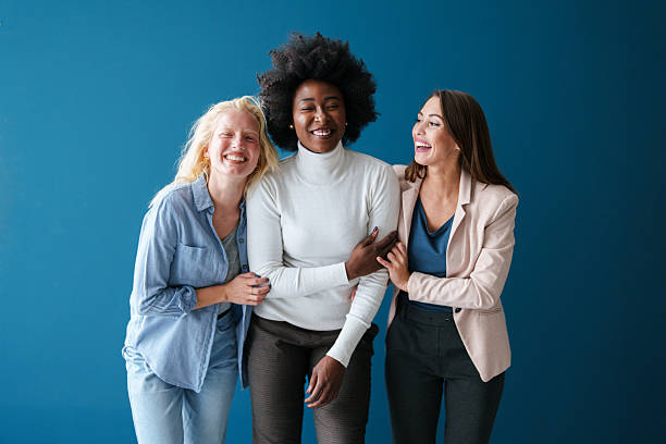 istock Three Multicultural Women Laughing Together in Bright Indoor Setting Against Blue Backdrop 2221779964