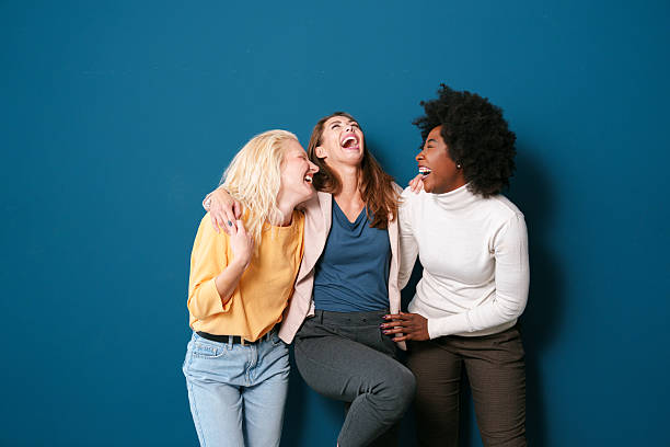 istock Three Multicultural Women Laughing Together Against a Vibrant Blue Background 2221779972