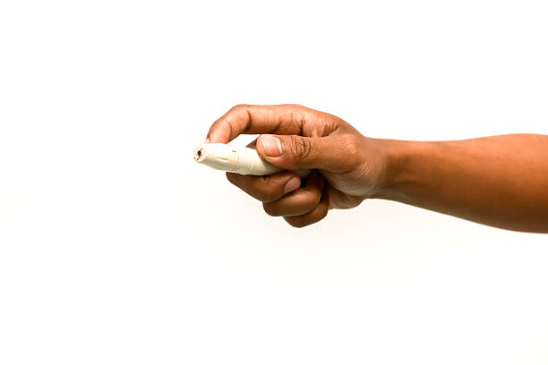 istock Close-up of a hand holding a lancing device for blood sugar testing on white background 2221782218
