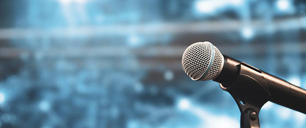 istock Microphone Public speaking background, Close up microphone on stand for speaker speech presentation stage performance with blur and bokeh light background. 2221786669