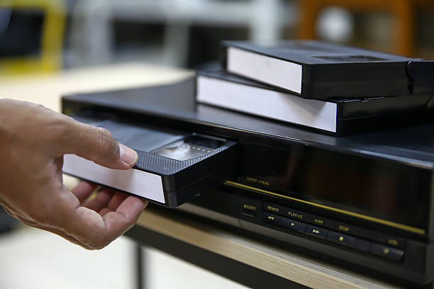 istock Close-up hand put or insert video cassette tape VHS old retro style on video record playback concept of vintage electric and electronic appliances multimedia player device old fashioned. 2221786800