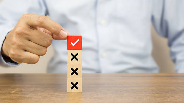 istock Hand choose check mark on cube wooden toy block stack with cross symbol for true or false changing mindset or way of adapting to change leader and transform quiz answer and poll concept 2221786881