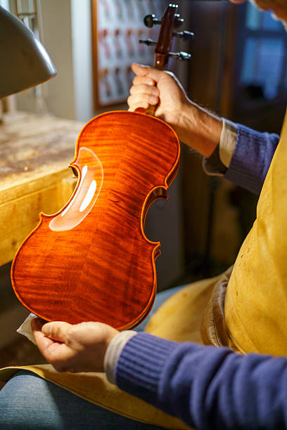 istock Skilled violinmaker inspecting handcrafted instrument amid workshop tools, highlighting meticulous woodworking expertise and musical instrument creation process 2221790297