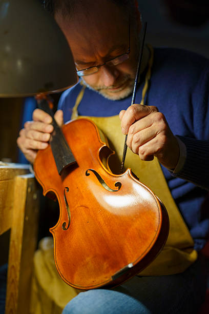 istock Skilled violinmaker meticulously works on a vintage violin in his workshop, using specialized tools and techniques to restore its beauty and sound 2221790300
