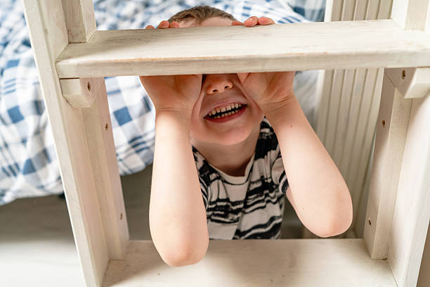 Boy Peeking Through Hole Of Yellow Play Equipment