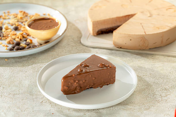 istock Cold cake slice topped with nuts and hazelnut cream, light background. 2221796360