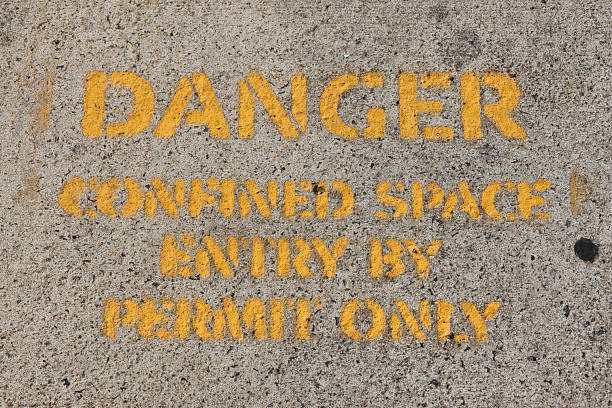 istock Danger - Confined Space - Entry By Permit Only sign painted in yellow on a concrete surface 2221797739
