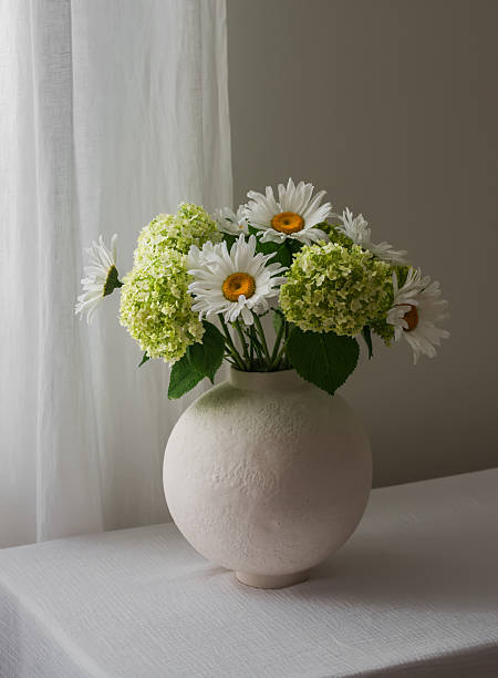 istock A bouquet of hydrangeas and daisies in a round ceramic vase on a table with a white tablecloth 2221799792