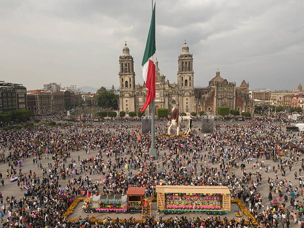 Mexico City, Mexico – November 1, 2024: Aerial drone footage captures the vibrant and elaborate Day of the Dead celebrations across various iconic locations in Mexico City. The images showcase a tapestry of altars adorned with marigolds, candles, and offerings, intricate calaveras and catrinas, and processions winding through historic streets and plazas. The unique perspective from the drone highlights the scale and beauty of this traditional Mexican holiday, offering a comprehensive view of the city's participation in honoring deceased loved ones. The scenes depict a city alive with cultural heritage, colorful decorations, and a deep reverence for life and death, all under the special ambiance of this significant annual event
