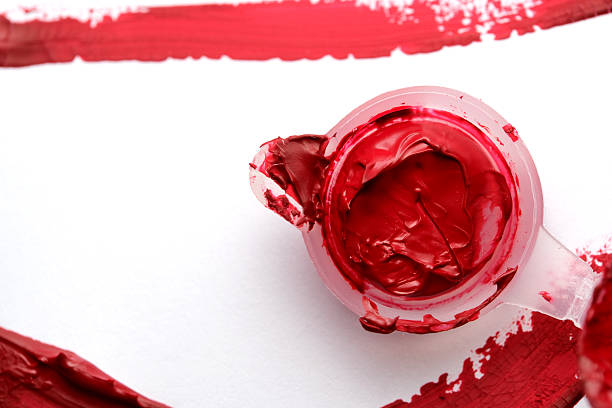 A jar of bright red paint sits on a white canvas, ready for creation.