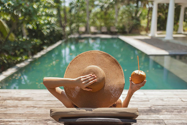 istock Woman Relaxing by Pool with Sun Hat and Coconut 2221801638