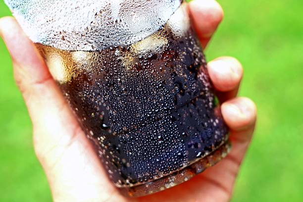 Hand holding Plastic cup of Iced Cola Soft Drink.