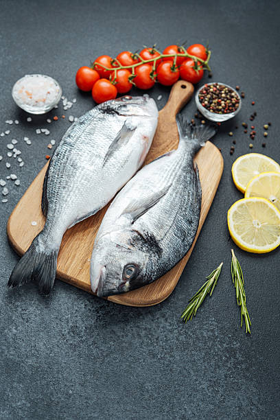 istock Dorado  fish with  tomatoes,  lemon and spices on cutting board 2221807588