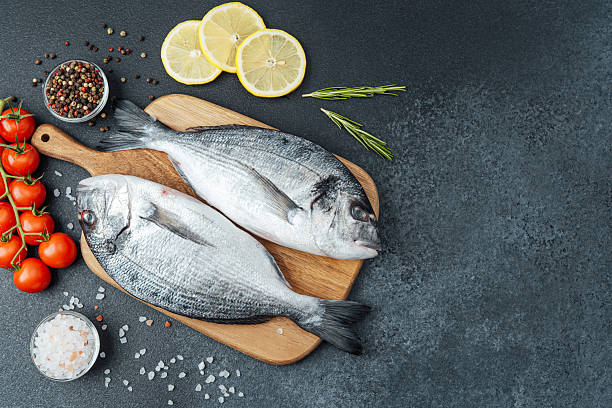 istock Dorado  fish with  tomatoes,  lemon and spices on cutting board 2221807591