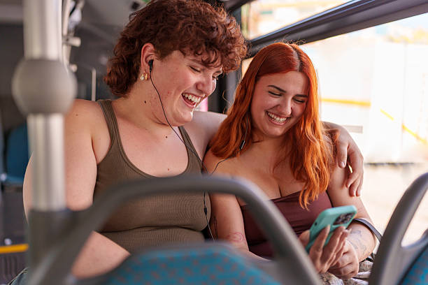 istock Two young women laughing while traveling by bus and using a smartphone 2221808768