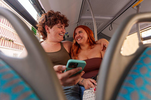 istock Two young women laughing and using a smartphone on a bus trip 2221808784